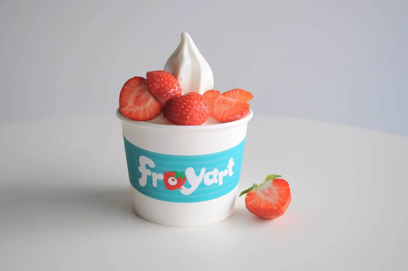 Κύπελλο froyart με παγωμένο γιαούρτι και φρέσκιες φράουλες από πάνω.