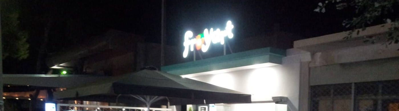 Η επιγραφή froyart αναμμένη πάνω από τη βεράντα του καταστήματος, ένα βράδυ.